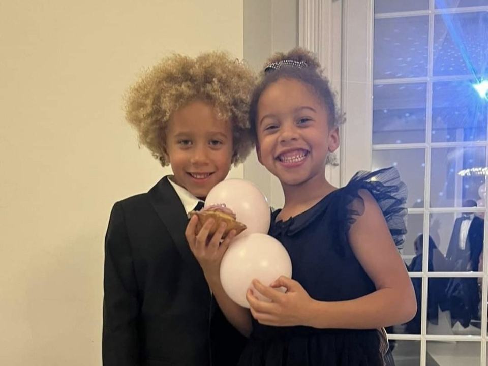 two twin children smiling holding a balloon at a party