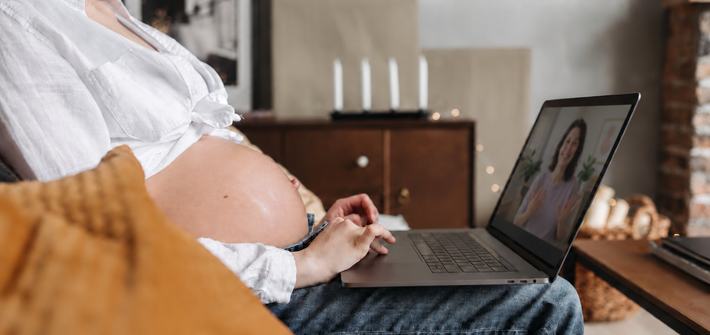 Expectant mother attending an online antenatal course while sitting in a cosy home environment, emphasizing remote work during pregnancy.