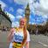 female marathon runner smiling holding her medal with the big ben in the background