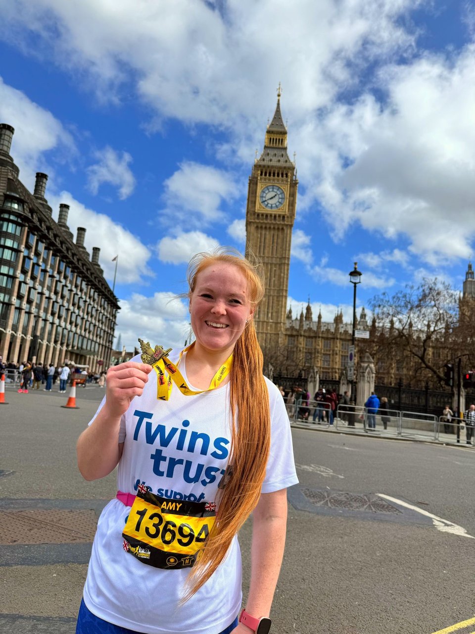 female marathon runner smiling holding her medal with the big ben in the background