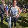 female marathon runner smiling with her hands on her hips standing in a sunny park