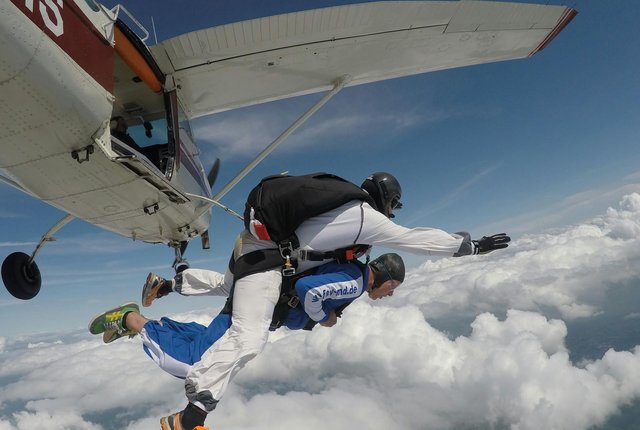 two people skydiving in tandem jumping off a plane in the sky